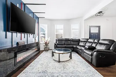 a living room with a black leather couch and a flat screen tv at Contemporary Private En-Suite - Steps to Cleveland Clinic in Cleveland