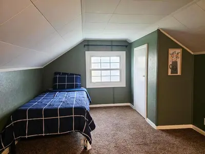 a bedroom with a blue bed and a window at Gather at the Cape in Youngstown
