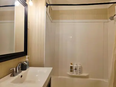 a white bathroom with a sink and a shower at Gather at the Cape in Youngstown