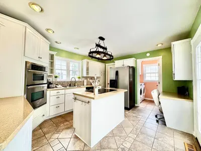 a kitchen with white cabinets and green walls at The Porch in Marion