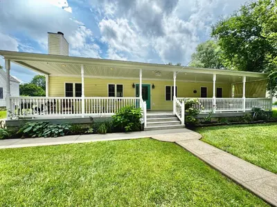 a yellow house with a porch and white railings at The Porch in Marion