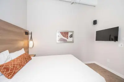 a bedroom with a white bed and a flat screen tv at The 333 Suites 201 - Stay for 6 in Cincinnati