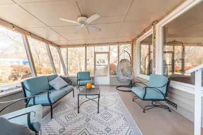 a screened in porch with chairs and a ceiling fan at The Corner House in Ripley