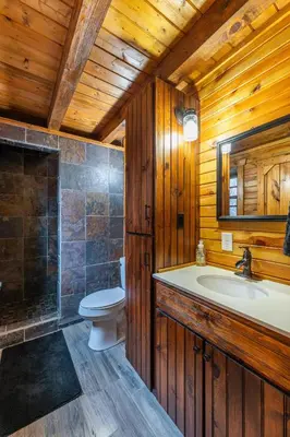 a wooden bathroom with a toilet and a sink at Wildlife Cabin