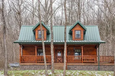 a log cabin with a green roof in the woods at Wildlife Cabin
