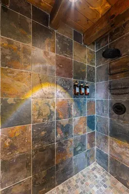 a bathroom with a shower with a tiled wall at Wildlife Cabin