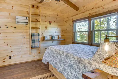 a log cabin bedroom with a bed and a window at Outdoor Oasis with Fire Pit and Dock Galion Log Cabin in Galion