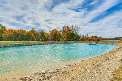 a pool of water on a beach with trees at Outdoor Oasis with Fire Pit and Dock Galion Log Cabin in Galion