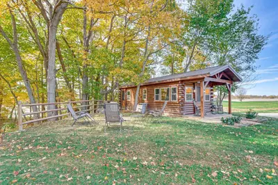 a log cabin with a porch and chairs in the yard at Outdoor Oasis with Fire Pit and Dock Galion Log Cabin in Galion