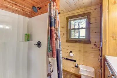 a bathroom with a shower curtain in a wooden room at Outdoor Oasis with Fire Pit and Dock Galion Log Cabin in Galion