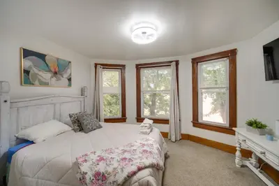 a bedroom with a white bed and windows at Central Akron Stay! Large Victorian Home with Yard in Akron
