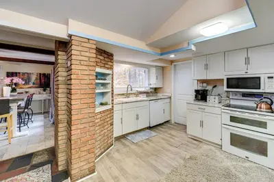 a kitchen with white cabinets and a brick wall at Easy Cleveland Access! Quiet Suburb Stay with Yard in Bedford
