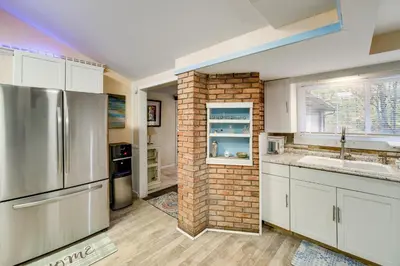a kitchen with white cabinets and a brick wall at Easy Cleveland Access! Quiet Suburb Stay with Yard in Bedford