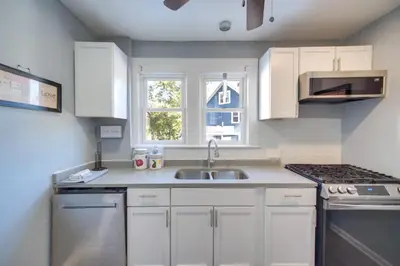 a kitchen with white cabinets and a sink and a window at Modern and Convenient! Group Stay in Highland Square in Akron
