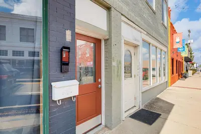a building with a red door on a street at 2 Mi to Ark Encounter! Walkable Williamstown Condo in Williamstown