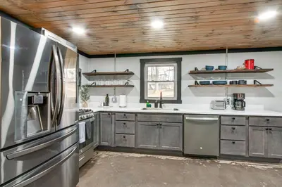 a kitchen with stainless steel appliances and wooden ceilings at Chène Cottage Near Burr Oak Lake and Trailheads! in Glouster