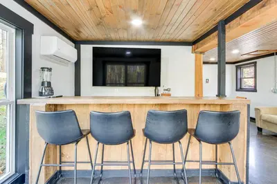 a kitchen with a bar with four blue chairs at Chène Cottage Near Burr Oak Lake and Trailheads! in Glouster