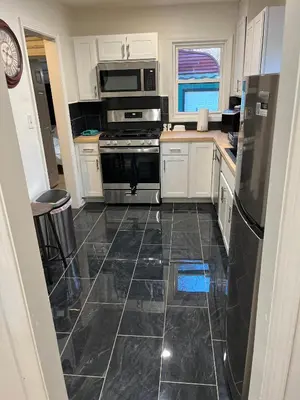 a kitchen with white cabinets and a black tile floor at Oilgate at Parkgate in Akron