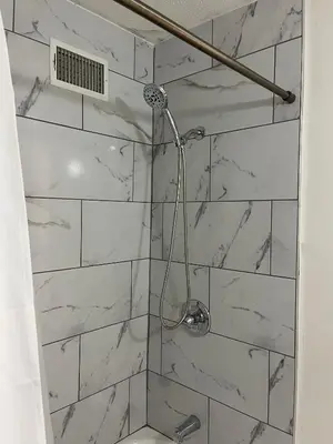 a bathroom with a shower with white marble tiles at Oilgate at Parkgate in Akron