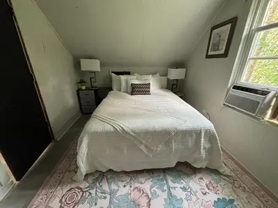 a bedroom with a bed with a white comforter at Great little house in Woodmere Beachwood Orange in Woodmere