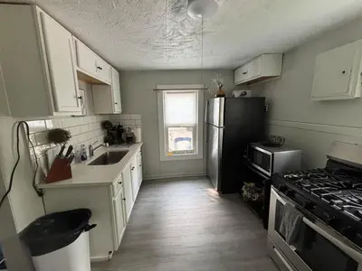 a kitchen with white cabinets and a black refrigerator at Great little house in Woodmere Beachwood Orange in Woodmere