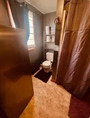 a bathroom with a toilet and a shower door at Del La Rose in Clarksburg