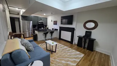 a living room with a blue couch and a kitchen at Quiet cheerful condo in the heart of OTR! in Cincinnati