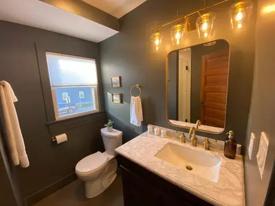 a bathroom with a sink and a toilet and a mirror at Totally renovated large family getaway! King bed