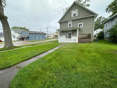 a house with a grass yard and a driveway at Totally renovated large family getaway! King bed