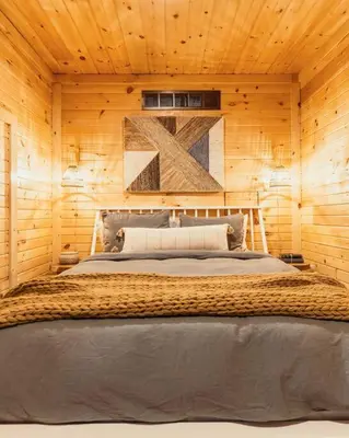 a bedroom with a large bed in a wooden wall at Creekside Hocking Hills Cabin-Game Shed Hot Tub in South Bloomingville