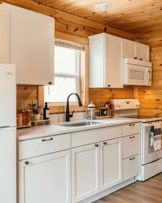 a kitchen with white cabinets and a sink at Creekside Hocking Hills Cabin-Game Shed Hot Tub in South Bloomingville