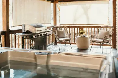 a balcony with two chairs and a stove on a deck at Creekside Hocking Hills Cabin-Game Shed Hot Tub in South Bloomingville