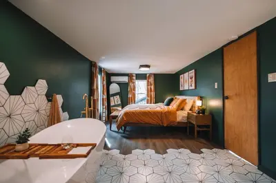 a bedroom with a bed and a tub in a room at Emerald Edge Hocking Hills Midcentury Cabin & Hot Tub in South Bloomingville