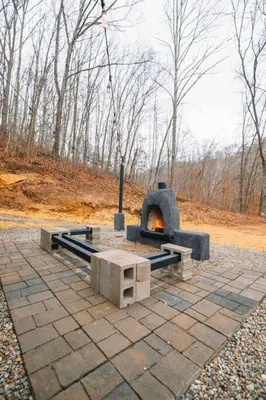 a stone oven with a fire in a park at Emerald Edge Hocking Hills Midcentury Cabin & Hot Tub in South Bloomingville
