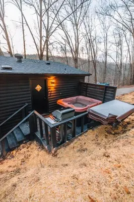 a small cabin with a sauna and a table and a grill at Emerald Edge Hocking Hills Midcentury Cabin & Hot Tub in South Bloomingville