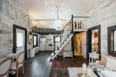 a living room with a staircase and a room with a couch at Victorian French Cottage - Hot Tub in Hocking Hills in South Bloomingville