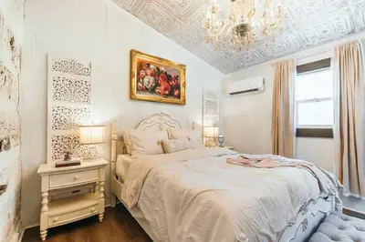 a white bedroom with a bed and a chandelier at Victorian French Cottage - Hot Tub in Hocking Hills in South Bloomingville