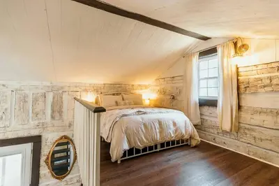 a bedroom with a bed in a room with wooden walls at Victorian French Cottage - Hot Tub in Hocking Hills in South Bloomingville
