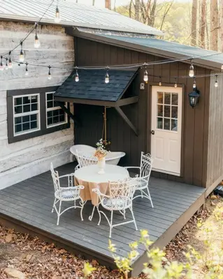 a patio with a table and chairs on a wooden deck at Victorian French Cottage - Hot Tub in Hocking Hills in South Bloomingville