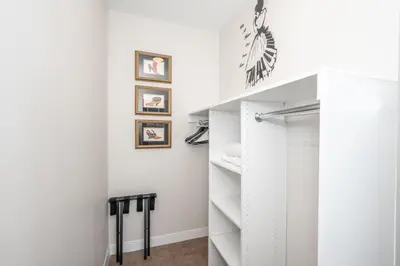 a walk in closet with white cabinets and pictures on the wall at The 333 Suites 302 - Stay for 6 in Cincinnati