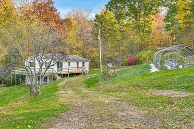 a house on the side of a hill with a driveway at Dirt Road Digs - Quiet Home in Lakeville!
