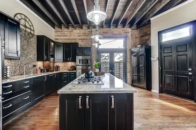 a kitchen with black cabinets and a large island at Dayton Loft close to DT Oregon UD in Dayton