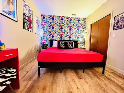 a bedroom with a red bed and a colorful wall at Radical 80's Getaway! A Blast From The Past! in Sandusky