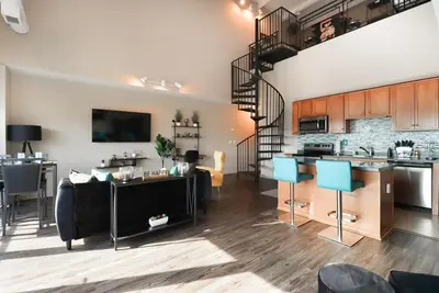 a kitchen and living room with a spiral staircase in a apartment at Downtown Sleeps 8 By Cedar Point & Sports Force! in Sandusky