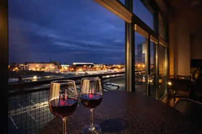 two glasses of wine sitting on a table on a balcony at Downtown Sleeps 8 By Cedar Point & Sports Force! in Sandusky