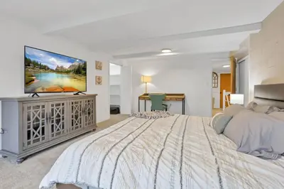 a bedroom with a large bed and a flat screen tv at Canary Cottage in Thornville