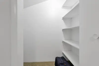 a white walk in closet with white shelves at Canary Cottage in Thornville