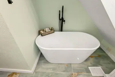 a white bath tub sitting in a corner of a bathroom at Canary Cottage in Thornville