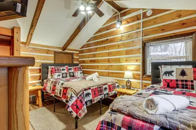two beds in a room with wooden walls at Lake Access and Hot Tub! Serene Rockbridge Cabin in Rockbridge
