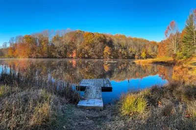a picnic table sits in front of a lake at Lake Access and Hot Tub! Serene Rockbridge Cabin in Rockbridge